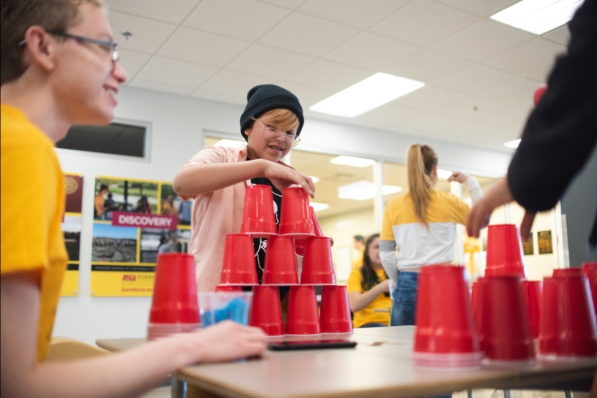 young people make stacks of red plastic cups