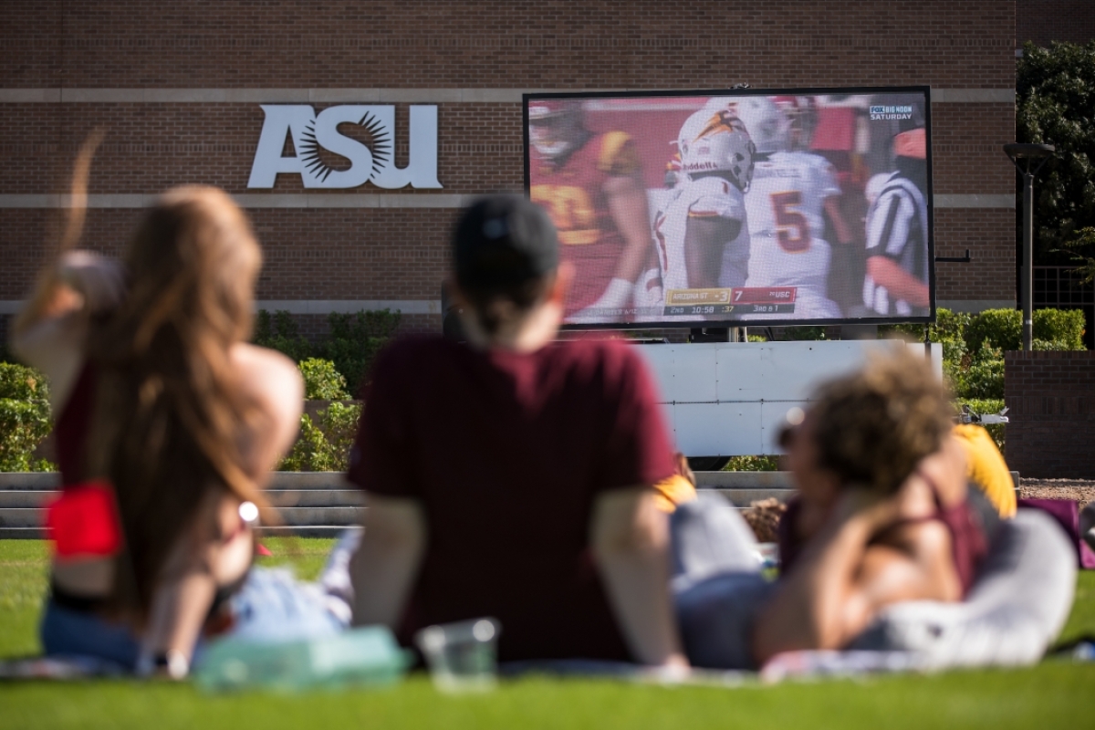 Students watch an ASU football game on a giant TV on the West campus