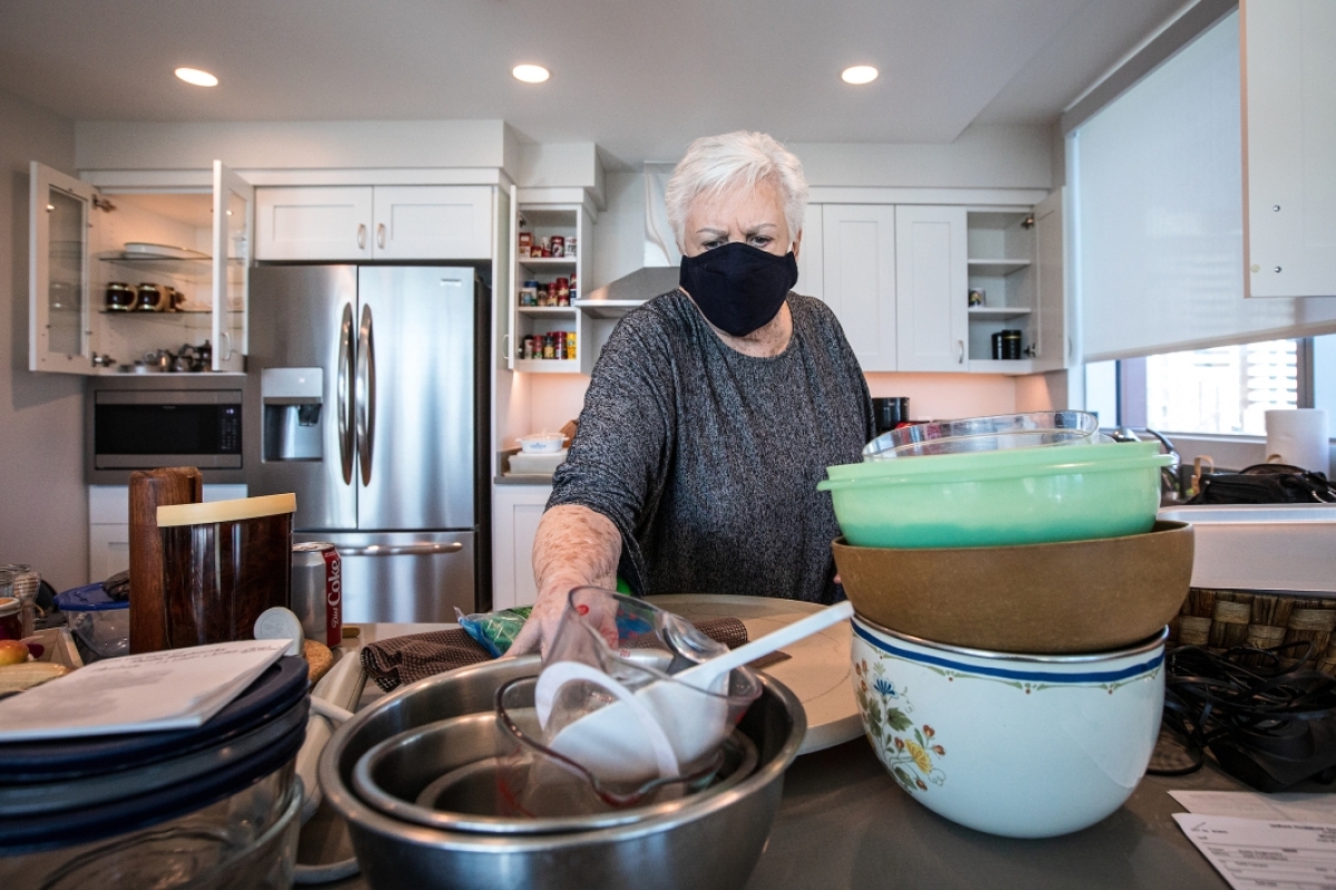 A woman in a mask unpacks dishes and bowls in her new kitchen