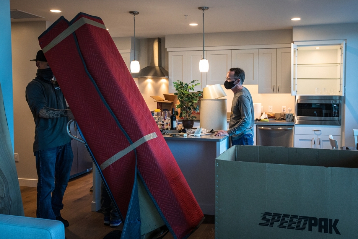 A man moves a tall piece of furniture into a new apartment