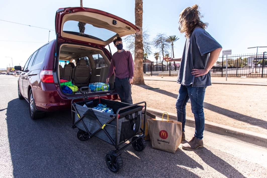 Two young men load food and water into a wagon to distribute to the homeless