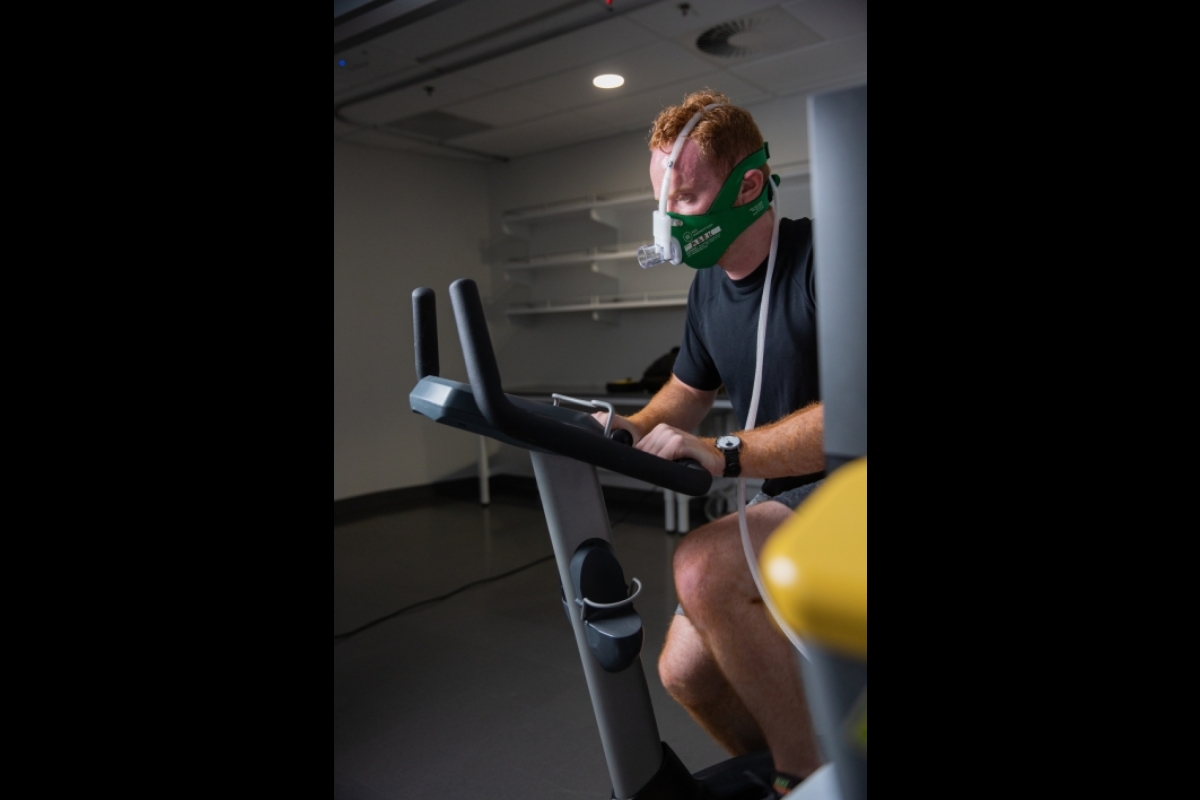 A man on a stationary bike wears a mask to measure oxygen
