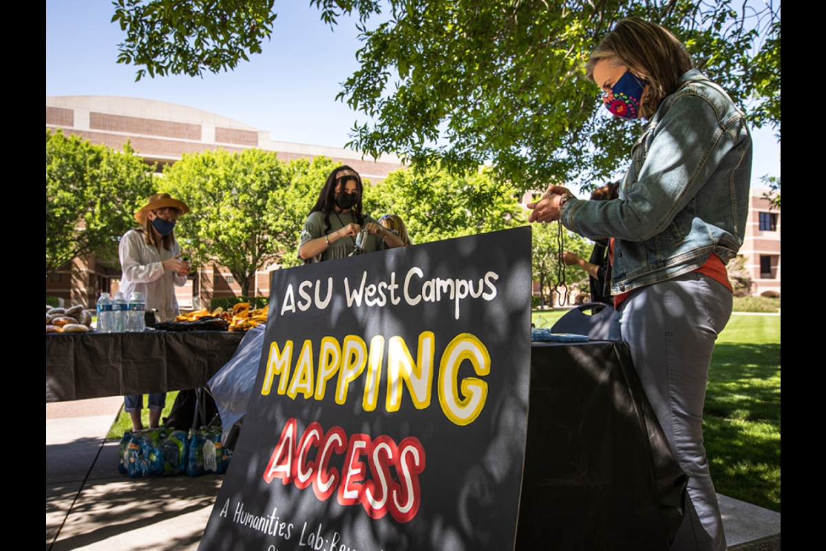 two people at outdoor table that says ASU West Campus Mapping Access