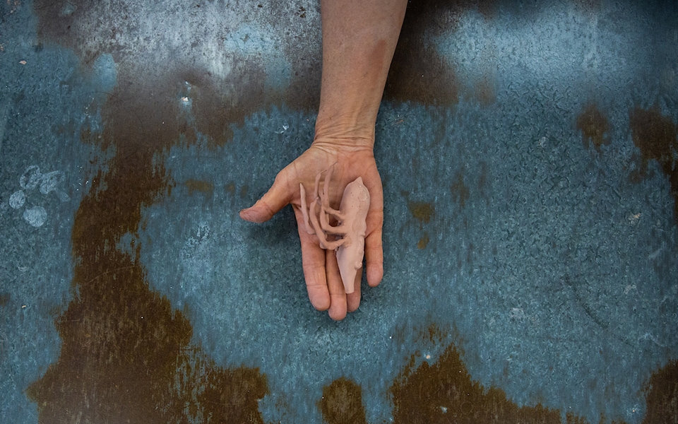 Hand holding a small glazed piece of ceramic artwork