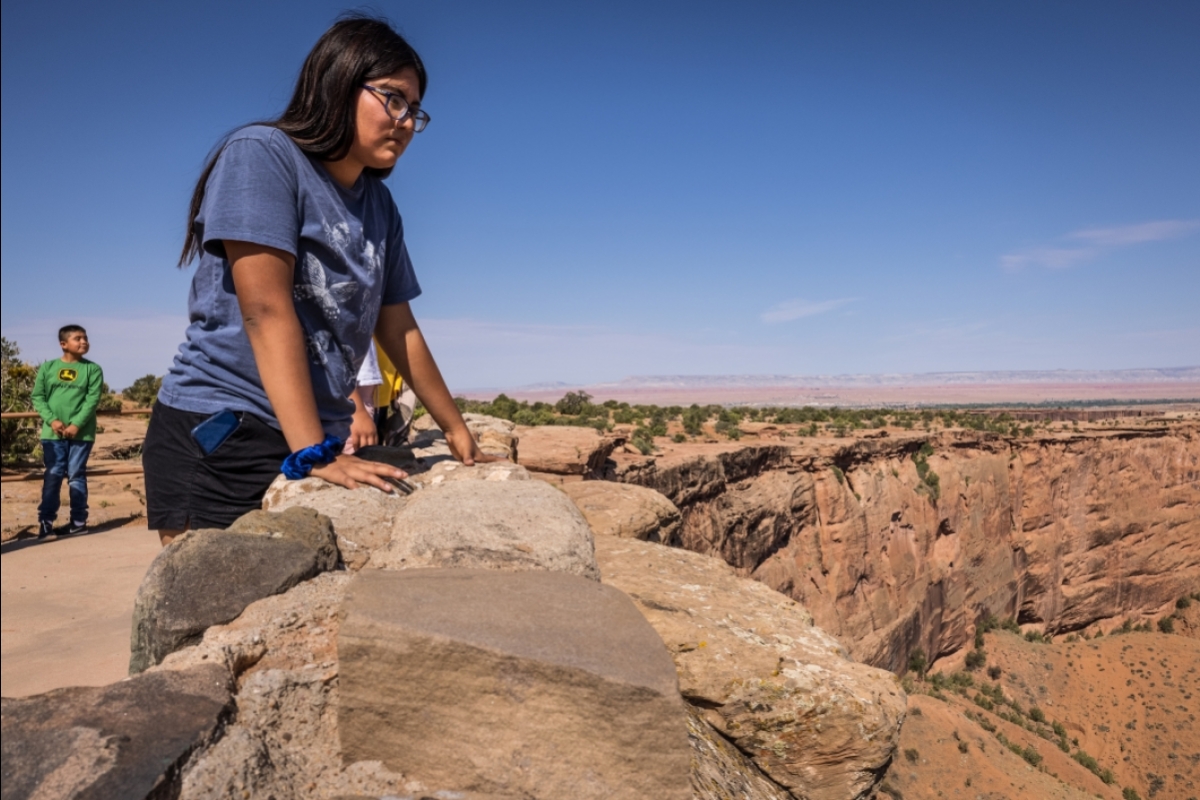 A young Navajo woman looks over the edge of Canyon de Chelly from an overlook