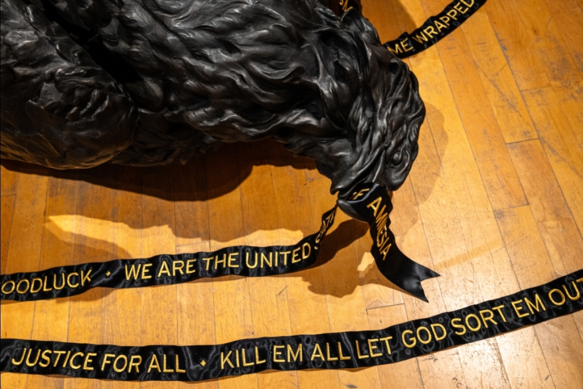art installation of dead black bird with ribbon in mouth