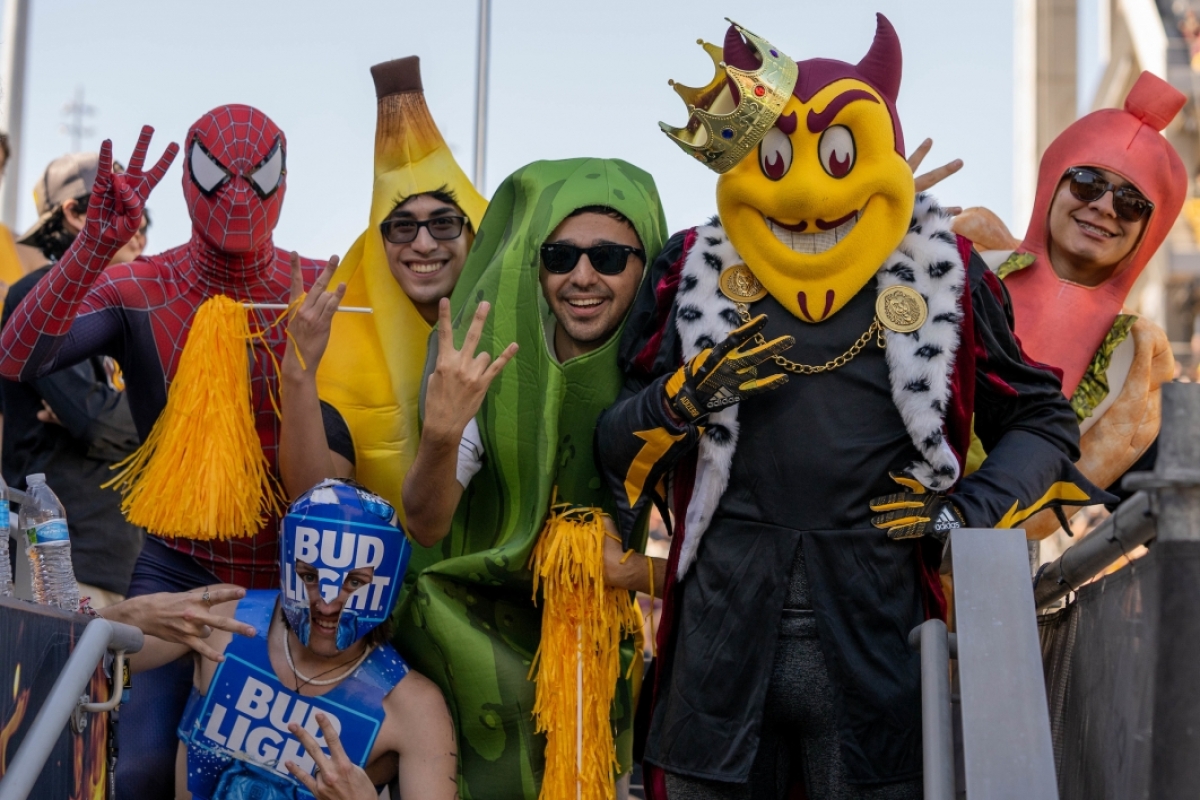 Students in a variety of Halloween costumes pose with Sparky dressed in Homecoming regalia
