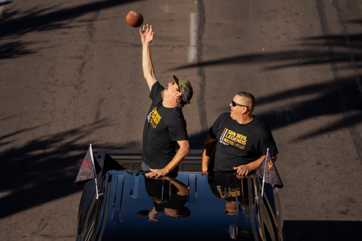 A football alum reaches up for a thrown football during the Homecoming parade