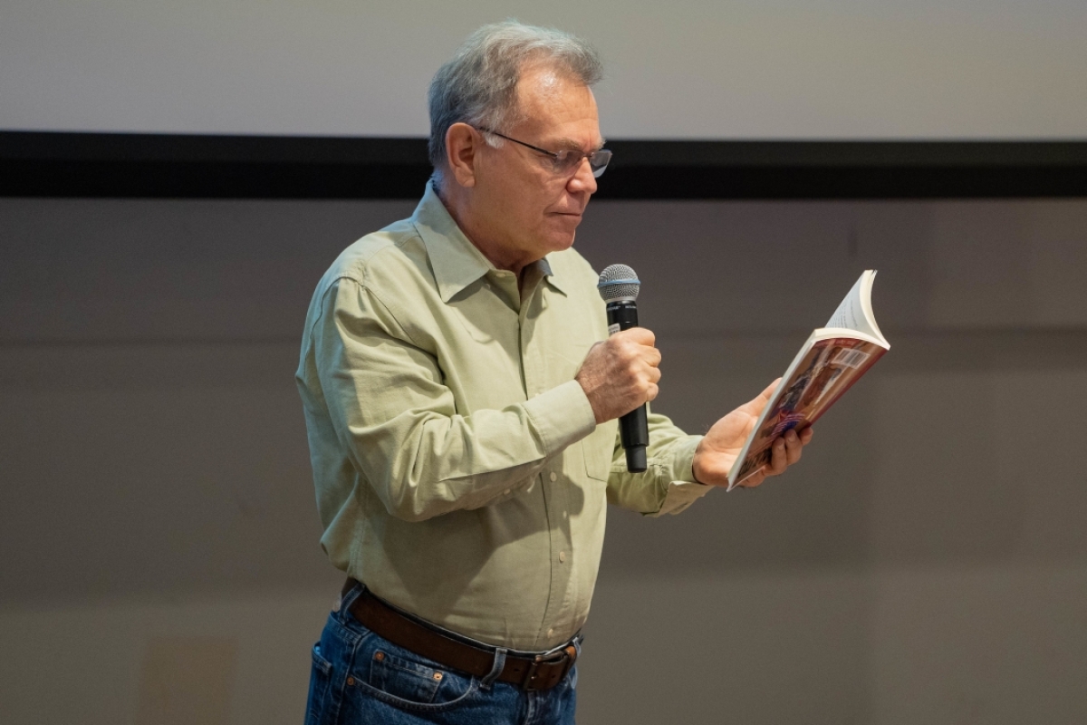 man holding a book and speaking into a microphone