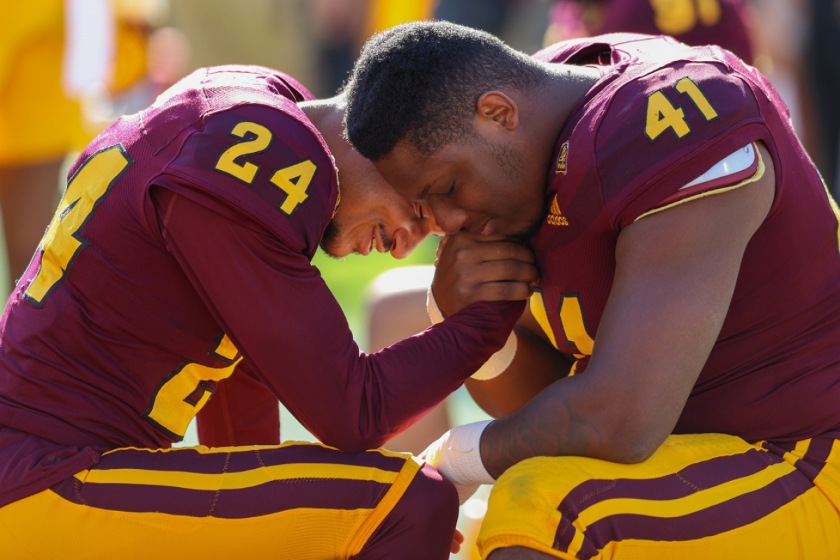 Two football players praying before game