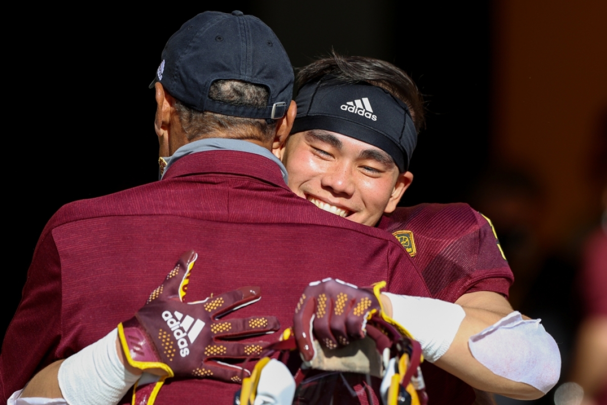 coach and football player hugging before game