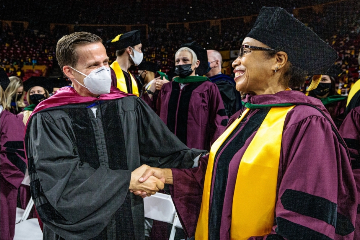 professor and doctoral student shaking hands at graduation