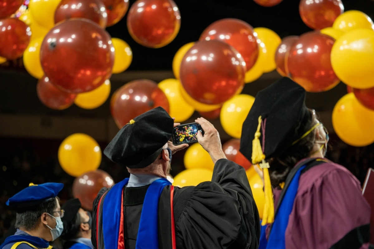 man taking photo of balloons at graduation