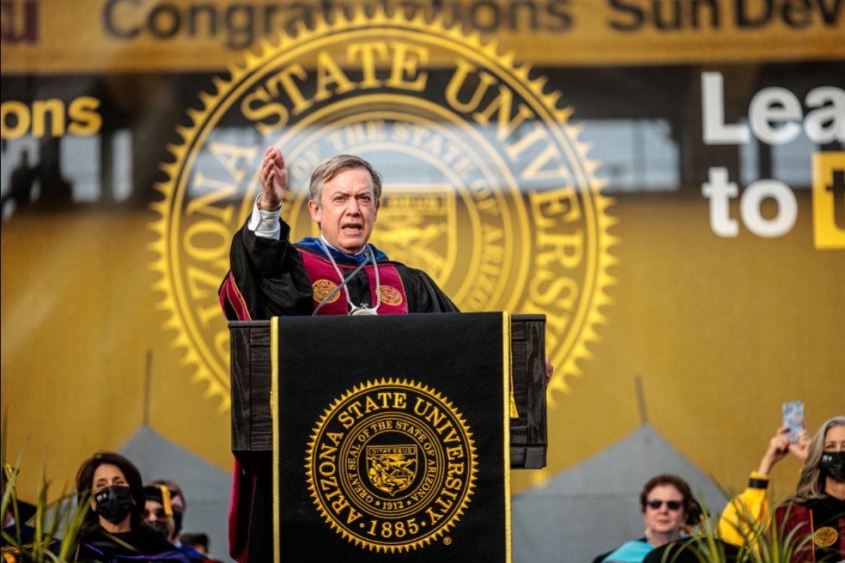 President Crow speaking at a lectern on stage at graduation
