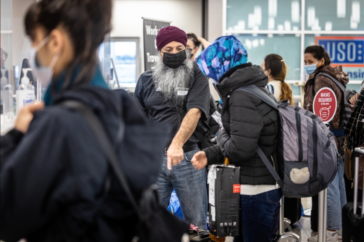 A man directs passengers standing in line at an airport