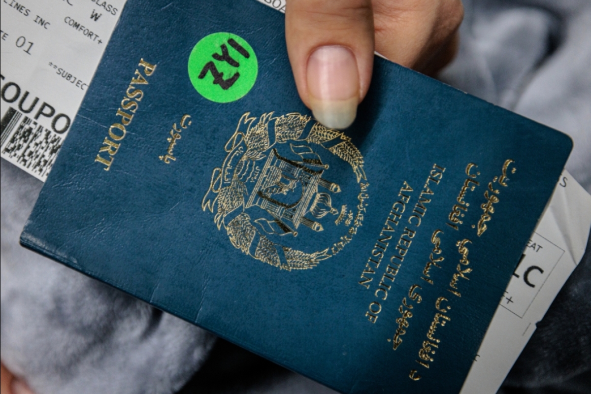 A closeup of a woman holding an Afghan passport with a plane ticket tucked inside