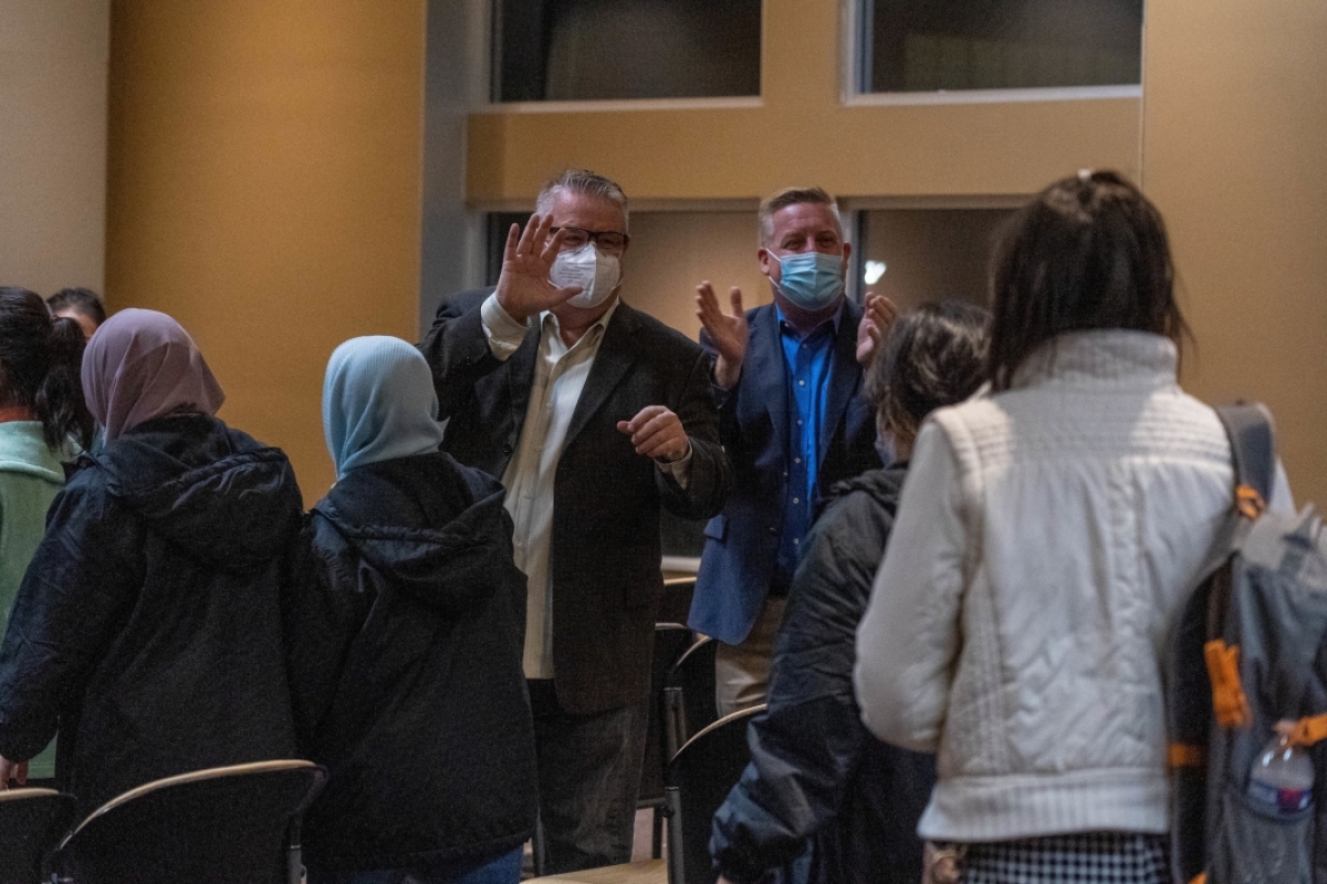 Two men clap as the Afghan refugee women enter a room at the Memorial Union