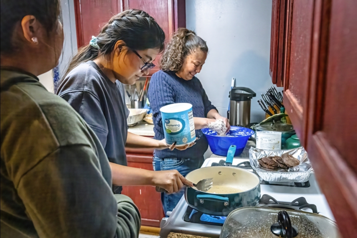 Three women make frybread in a kitchen