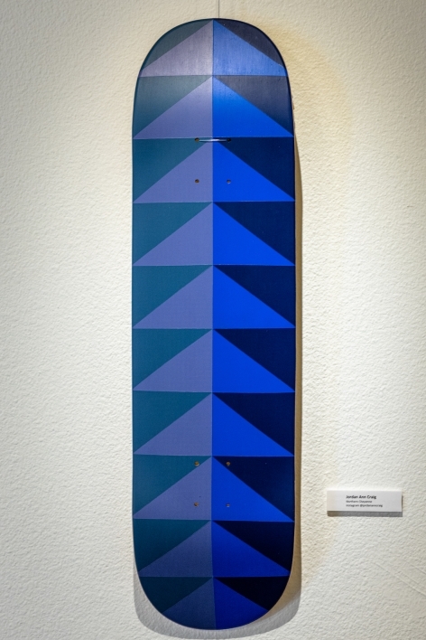 Skateboard painted with dark blue and purple geometric shapes.