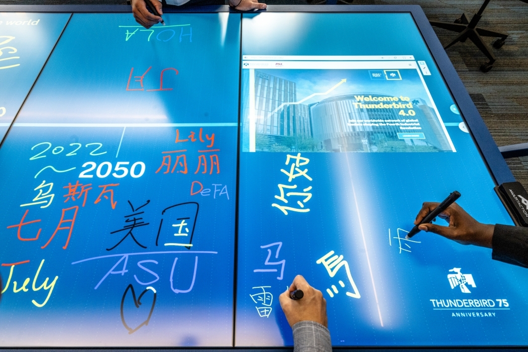 Hands holding styluses write on an electronic touch table