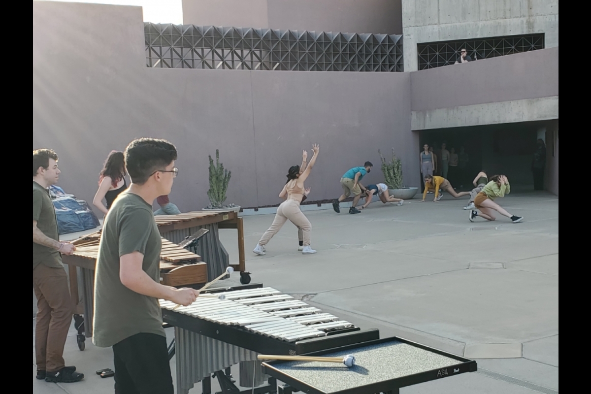 People playing instruments outside of a building while other people dance.