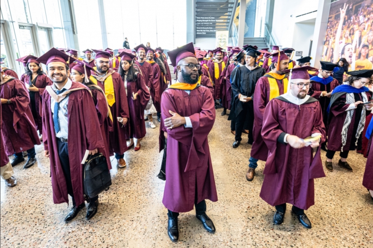 Students in caps and gowns line up in a grid before entering a ceremony
