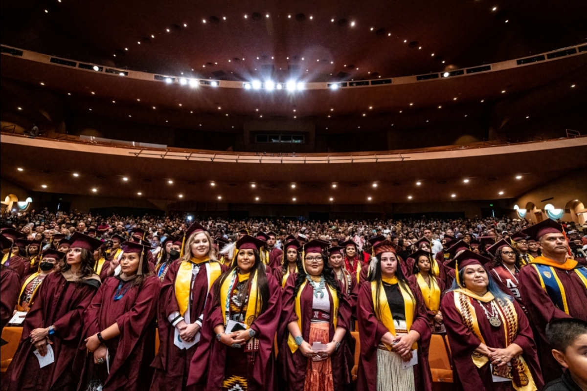 Graduates in caps and gowns fill an auditorium