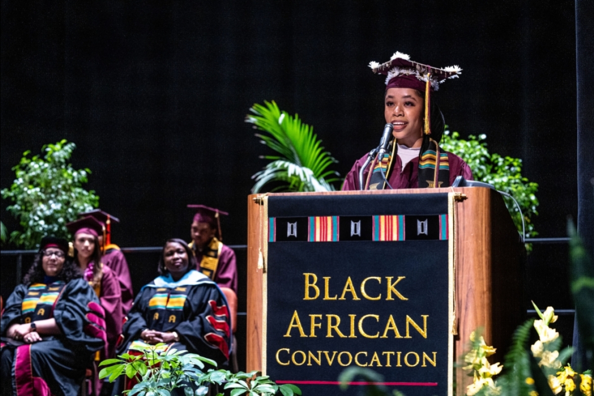 A woman speaks at a lectern that has a banner with the words Black African Convocation on the front