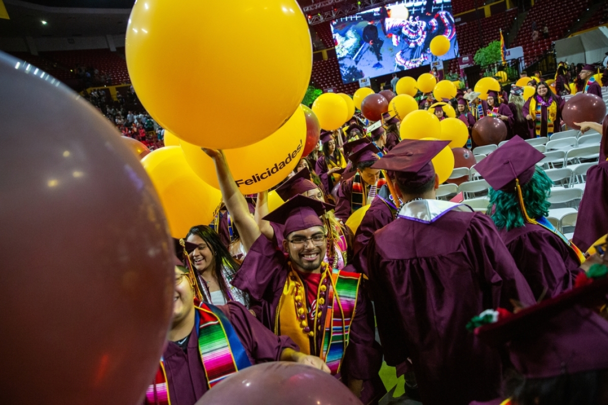 Male graduate holding up balloon as he leaves commencement ceremony