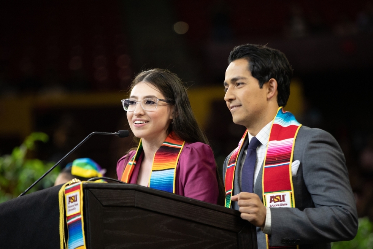 Two people speaking at lectern during commencement