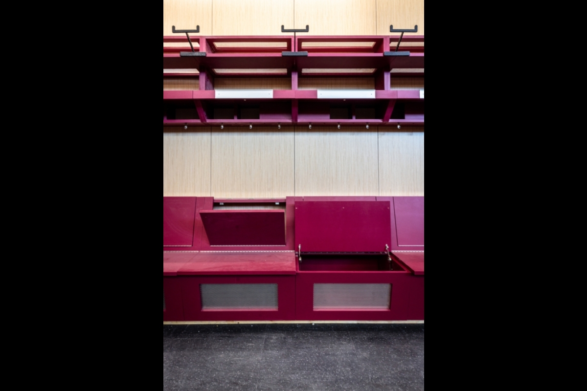 An empty locker room with compartments inside the bench seating to hold dirty uniforms
