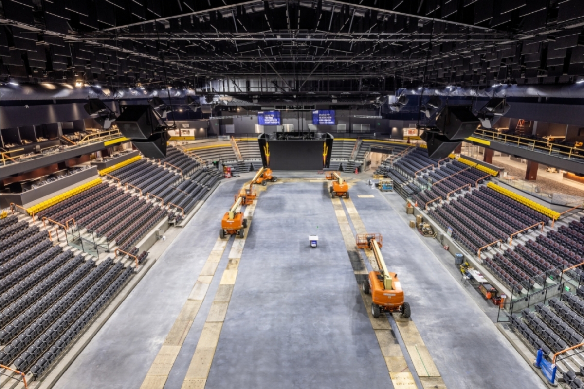 A hockey arena is shown under construction with forklifts on what will be the ice