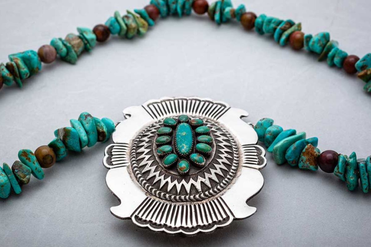 A medallion made out of silver and turquoise
