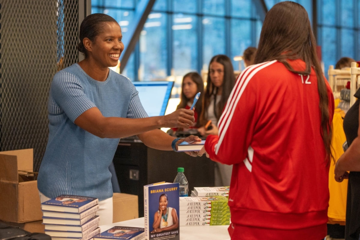 Woman signing book for young girl
