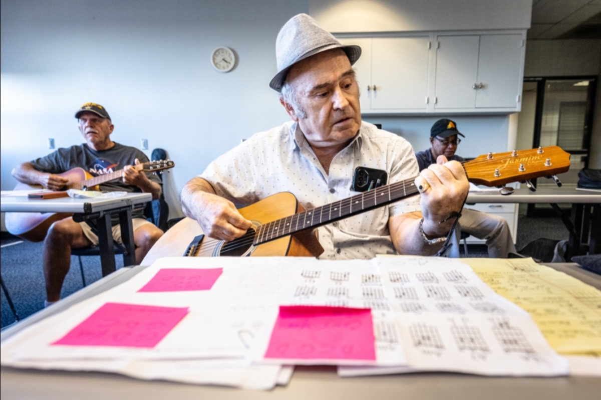 Man playing guitar with sheet music in front of him