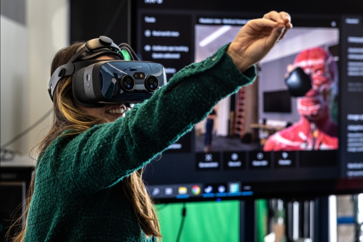 Woman wearing a VR headset and reaching out with her arm in front of her.