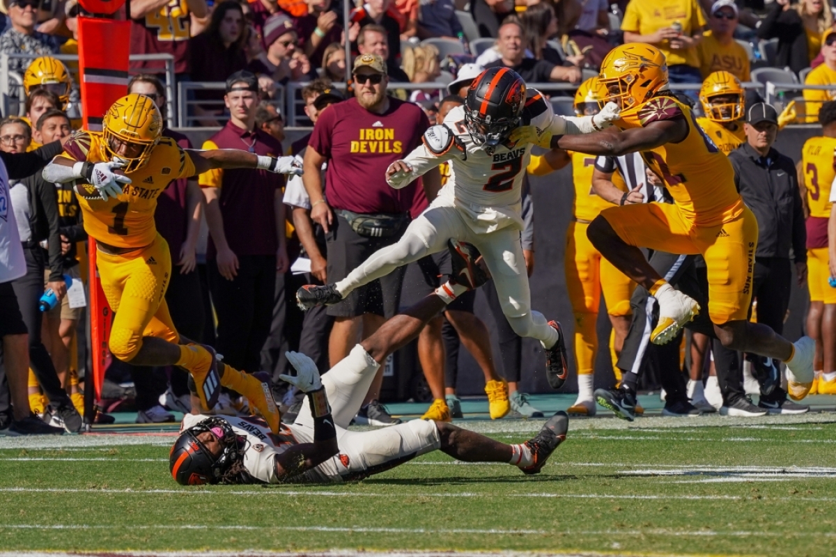 ASU football player jumps over Oregon State player who is on the field