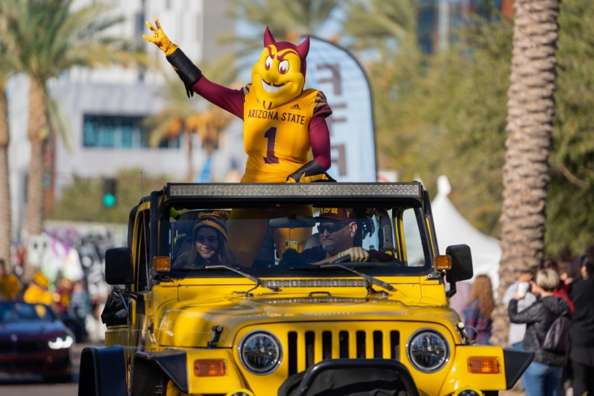 Sparky mascot riding on top of Jeep in parade