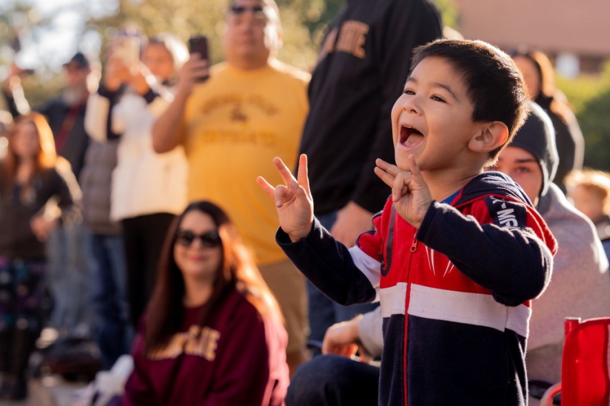 Little boy flashing pitchfork signs with his hands during parade