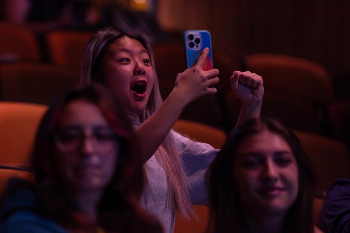 A woman cheers while recording the launch on her phone