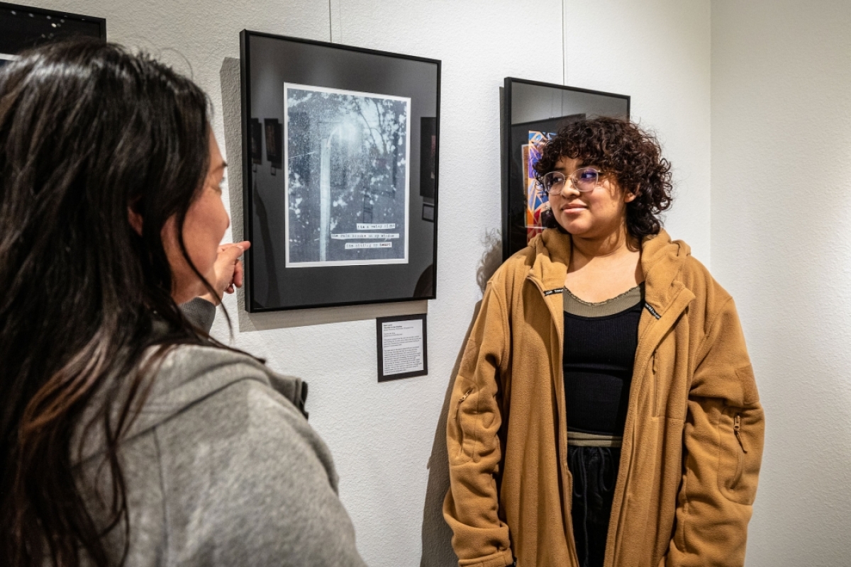 Mother and student talk next to hanging art pieces at exhibit