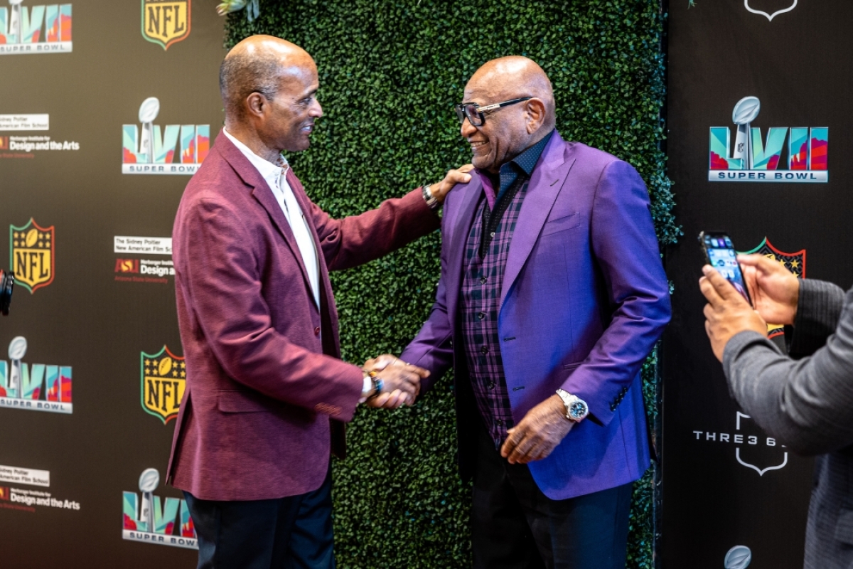 Two men shaking hands at red carpet event
