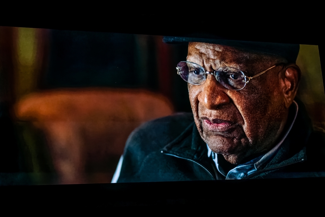 Closeup of and older Black man on screen during documentary