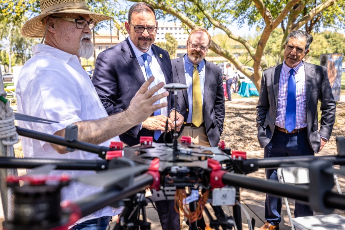 Group of men talking and looking at a drone