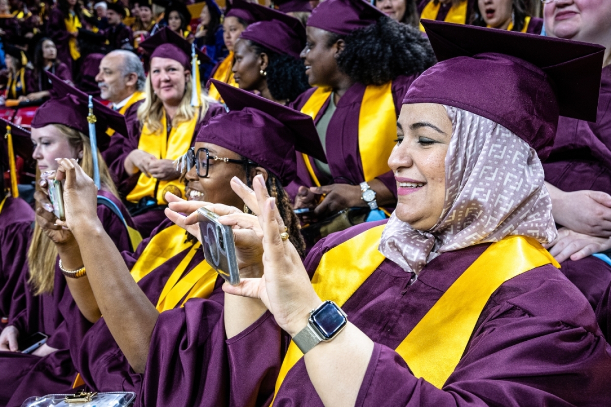 Graduates taking photos with their phones during commencement