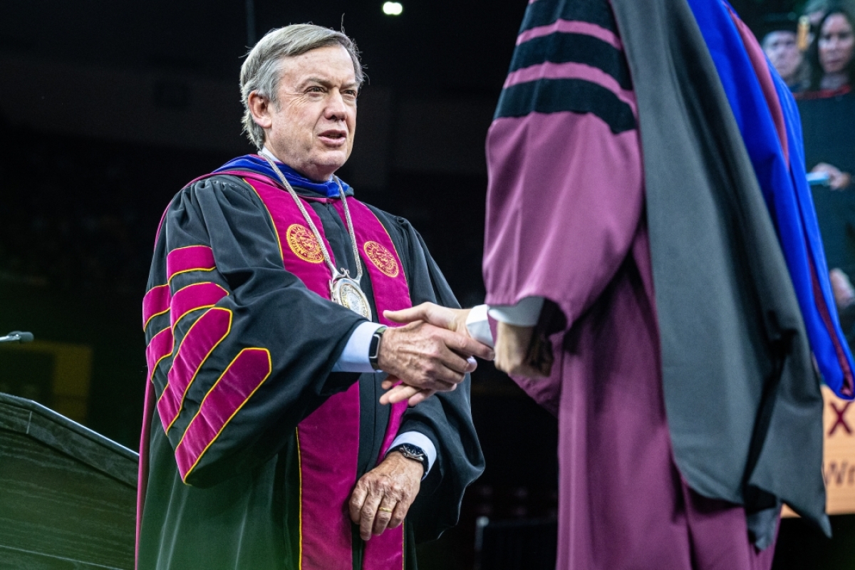 ASU President Michael Crow shakes graduate's hand during commencement