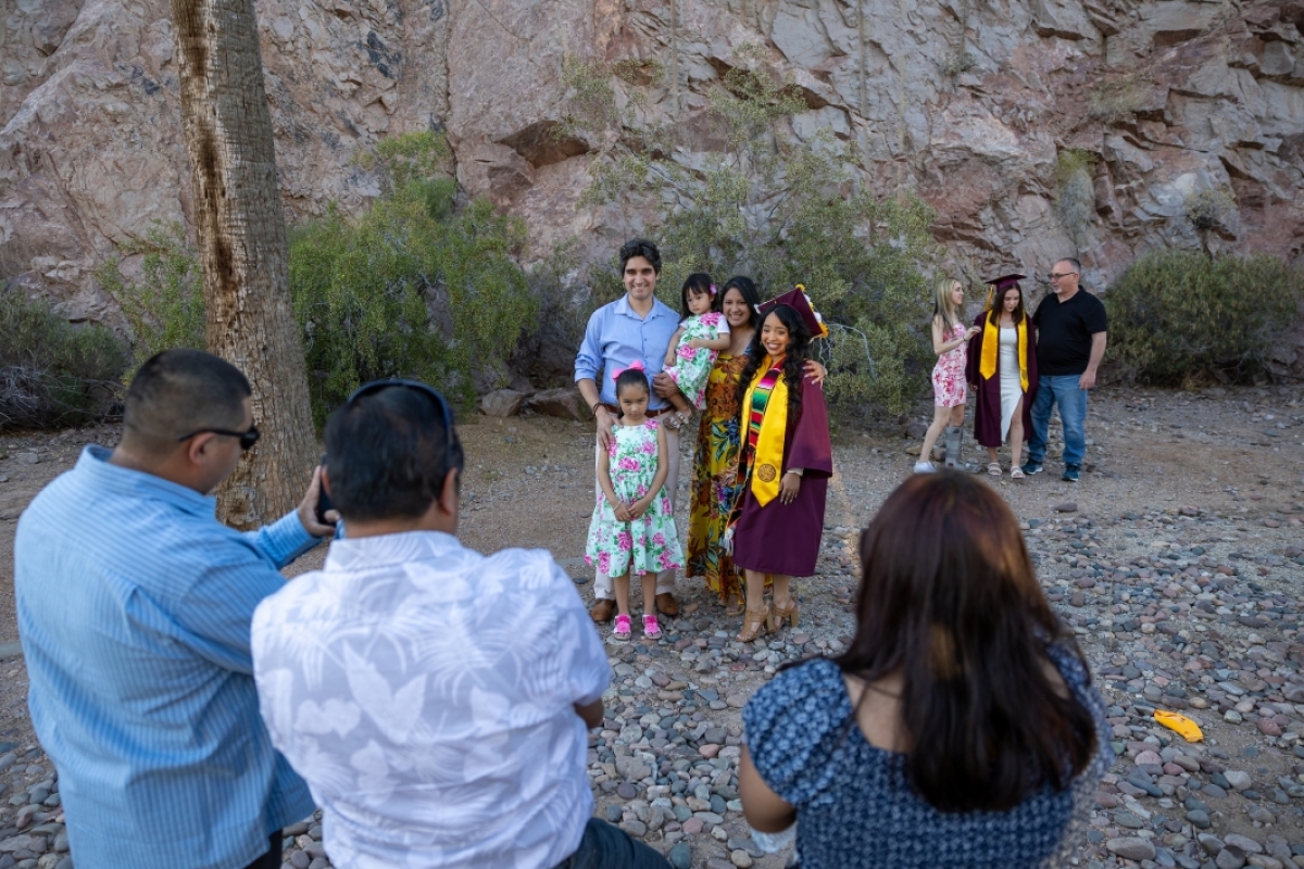 Families posing for photos in front of desert landscape before commencement