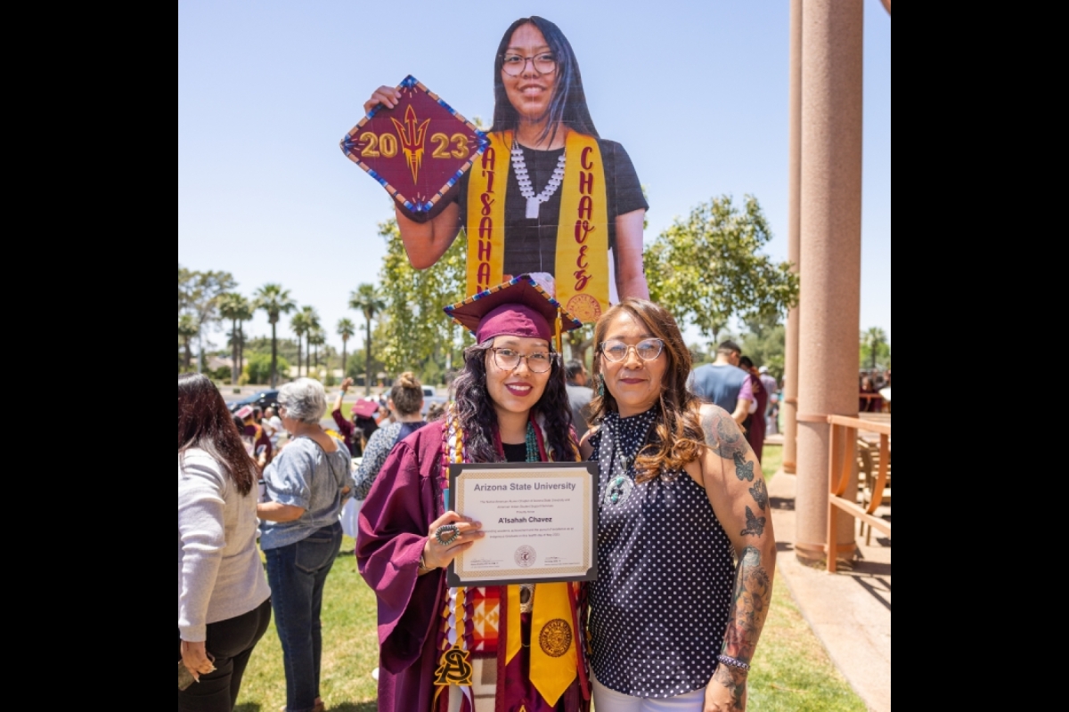 Graduate poses with her mom and cardboard cutout of herself after graduation