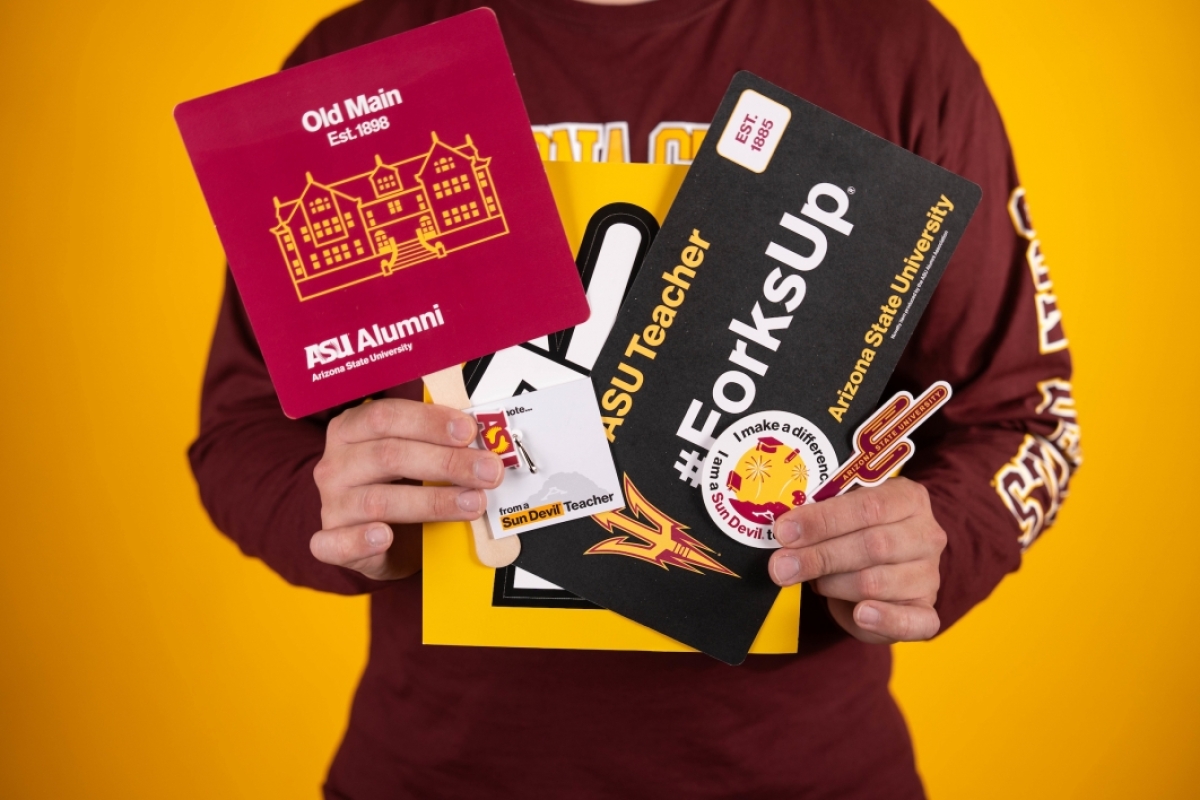 Hands holding ASU promotional materials.