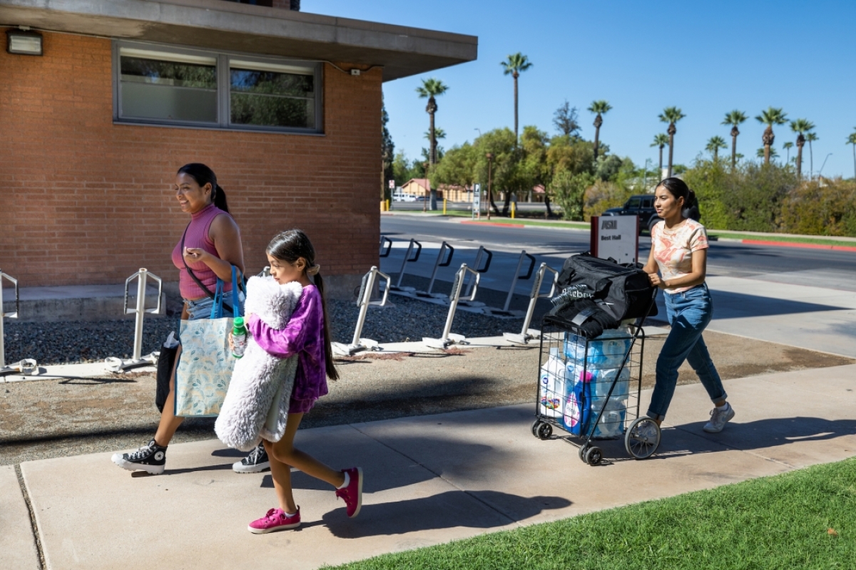 Family walking with dorm room items on campus